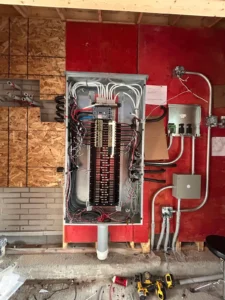 450 Booth Street electrical distribution panel with conduit, breakers, and service wiring during construction.