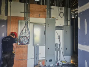 A&W Restaurant electrical room with distribution panels, conduit runs, data wiring, and Ottawa Electric technician during buildout.