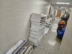 Dr. F.J. MacDonald School lighting upgrade showing removed light fixtures stacked in a hallway during renovation.