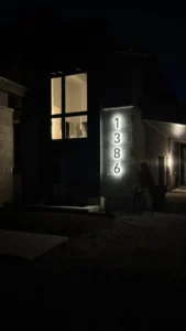 InHarmony Developments custom home exterior at night with illuminated address numbers, exterior lighting, and finished residential electrical work.