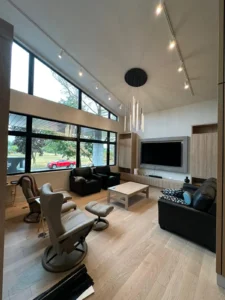 InHarmony Developments custom home living room with decorative chandelier, track lighting, large windows, and finished residential electrical work.