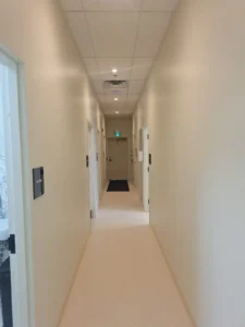 Dental & Plastic Surgery Facility corridor with recessed ceiling lights, emergency exit signage, and finished medical electrical fit up.