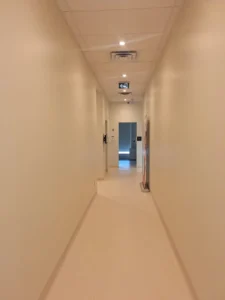 Dental & Plastic Surgery Facility corridor with recessed ceiling lights, exit signage, ceiling devices, and finished medical electrical fit up.