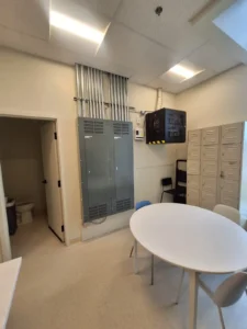 Dental & Plastic Surgery Facility equipment room with electrical panels, conduit runs, network cabinet, and finished lighting.