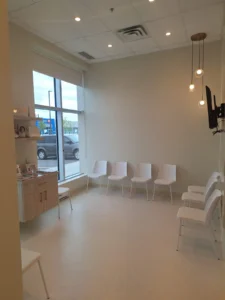 Dental & Plastic Surgery Facility waiting room with recessed ceiling lights, pendant fixtures, and finished patient seating area.