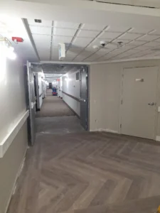 Windsor Park renovation corridor at Old Faulks Home with fire alarm devices, wall lighting, and mag lock door integration.