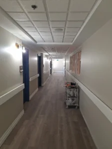 Windsor Park renovation hallway at Old Faulks Home with wall lighting, ceiling devices, and updated corridor finishes.